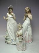 TWO LARGE NAO FIGURES OF YOUNG GIRLS IN COSTUME HOLDING FLOWERS, tallest H 33 cm, together with a