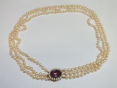 A HALLMARKED 9 CARAT GOLD CLASP TRIPLE ROW OF CULTURED PEARLS WITH LARGE AMETHYST, amethyst measures