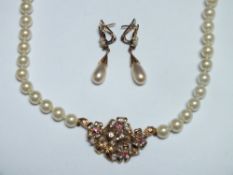 A MODERN PEARL AND GEMSET NECKLACE, the central yellow metal decorative panel set with red and clear