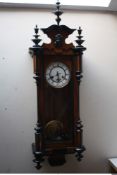 A LATE 19/EARLY 20TH CENTURY WALNUT VIENNA WALL CLOCK, the enamel dial with Roman numerals, carved