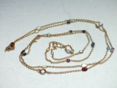 AN UNMARKED YELLOW METAL FLAPPER LENGTH CHAIN SET WITH POLISHED AND FACETED SEMI-PRECIOUS GEMSTONES,