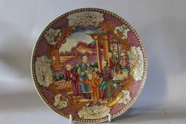 AN ORIENTAL FAMILLE ROSE SHALLOW PLATE, decorated with figures beside a pagoda, animal and floral
