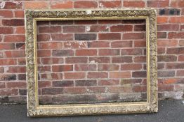 A 19TH CENTURY DECORATIVE GOLD FRAME, frame W 11 cm, rebate approx 88 x 114 cm