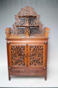 A CARVED ORIENTAL STYLE TABLE CABINET, the pierced fretwork doors opening to three drawers with