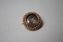 AN EDWARDIAN YELLOW METAL AND SEED PEARL LOCKET BROOCH, of circular form, with portrait photo to