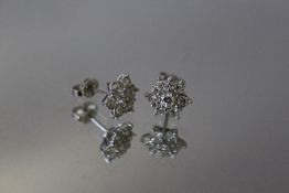 A PAIR OF SEVEN STONE DIAMOND EARRINGS, in a foral style, butterfly stamped 750, W 1 cm