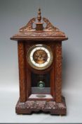 A LATE 19TH CENTURY CARVED OAK MANTEL CLOCK, the enamel dial with Roman numerals, visible anchor