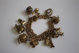 A 9CT GOLD AND YELLOW METAL CHARM BRACELET, charms include a railway lamp, kettle and fish etc.