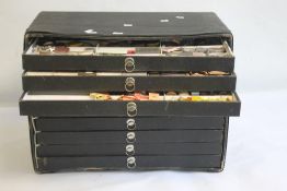 A LARGE QUANTITY OF POCKET WATCH PARTS STORED IN A NINE DRAWER CABINET, to include movements,