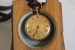 A YELLOW METAL (Marked 18ct) CONTINENTAL FOB WATCH, contained in a folding wooden stand.