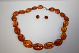 A SILVER CLASPED AMBER TYPE NECKLACE AND A PAIR OF CLIP ON EARRINGS