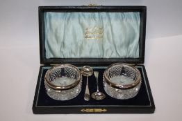 A PAIR OF BOXED SILVER RIMMED SALTS AND SPOONS