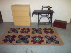 AN IKEA 4 DRAWER MAIN CHEST AN ANTIQUE RUG AND A SINGER HAND SEWING MACHINE IN CAST TABLE.