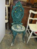 A HEAVY CAST IRON GREEN PAINTED OUTDOOR CHAIR WITH FIGURATIVE DETAIL
