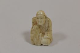 A VINTAGE NETSUKE IN THE FORM OF A KNEELING MAN