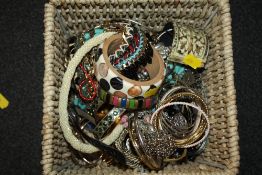 A BASKET OF COSTUME JEWELLERY TO INCLUDE BANGLES, NECKLACES ETC.