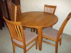 A CIRCULAR EXTENDING DINING TABLE AND FOUR CHAIRS