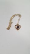 A 9 CT GOLD HEART SHAPED PENDANT SET WITH RED STONE ON A CHAIN