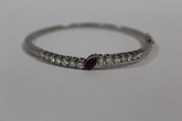 A BOXED LADIES WHITE METAL BANGLE SET WITH A CENTRAL MARQUIS CUT RUBY AND FOURTEEN PRINCESS CUT