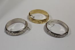 TWO HALLMARKED SILVER ENGRAVED BANGLES TOGETHER WITH A GOLD PLATED EXAMPLE