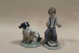 A NAO FIGURE OF A DOG AND A CAT TOGETHER WITH A NAO FIGURE OF A BOY WITH A PUPPY