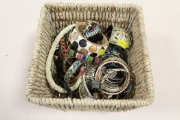 A BASKET OF COSTUME JEWELLERY TO INCLUDE BANGLES, NECKLACES ETC.