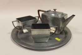 AN ART DECO HAMMERED FINISH PEWTER THREE PIECE TEA SERVICE ON TRAY, BY ARGENT