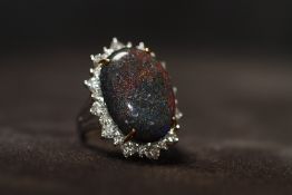 A WHITE GOLD BLACK OPAL AND DIAMOND RING. boxed. Black opal 13.16ct. Diamonds 1.14ct, Ring size N