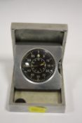 A MILITARY STYLE METAL CASED BLACK DIAL TRAVEL CLOCK MARKED D.A.C