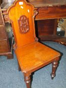 AN ANTIQUE MAHOGANY HALL CHAIR WITH CARVED DETAIL