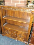 A REPRODUCTION CARVED OAK SMALL OPEN BOOKCASE WITH CUPBOARD BELOW H-95 CM W-84 CM