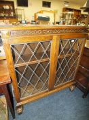 A REPRODUCTION CARVED OAK GLAZED BOOKCASE H-114 CM W-102 CM