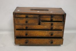 A VINTAGE WOODEN ENGINEERS TOOL CHEST FITTED WITH 8 DRAWERS AND A LIFT OFF FRONT PANEL,