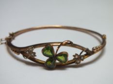 A 9CT GOLD SHAMROCK BANGLE, set with green peridot type stones with two further seed pearl set