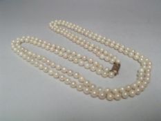 A DOUBLE STRAND HAND KNOTTED CULTURED PEARL NECKLACE WITH 9CT GOLD CLASP, shortest strand approx L