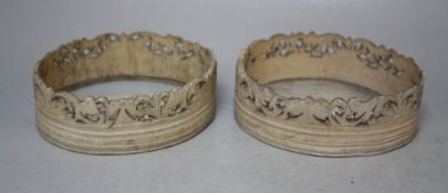 A PAIR OF 19TH CENTURY CARVED IVORY COASTERS, of oval outline, with pierced carved sides, Dia. 9