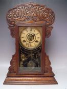 AN ANTIQUE OAK 'GINGERBREAD' MANTLE CLOCK OF TYPICAL FORM, with paper label to reverse, key,
