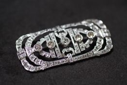 AN EDWARDIAN PLATINUM DIAMOND BROOCH WITH FILIGREE DESIGN, in a vintage box. Set with 5 graduated