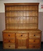 A LARGE ANTIQUE PINE KITCHEN DRESSER, having enclosed plate rack, the base with an arrangements of