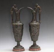 A PAIR OF BRONZE BACCHUS EWERS, seeing Bacchus squeezing a bunch of grapes into the ewer as he