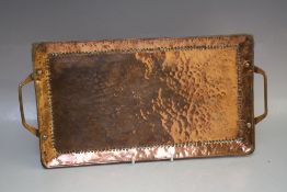 AN ARTS AND CRAFTS RECTANGULAR TWIN-HANDLED TRAY BY JOHN PEARSON, of typical hammered finish,