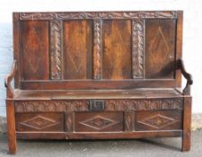 AN ANTIQUE OAK AND INLAID PANELLED SETTLE, the four panel high back with carved decoration and