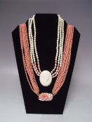 A TEN STRAND CORAL BEAD NECKLACE, with yellow metal mounted floral clasp carved in high relief,