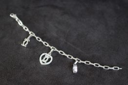 CARTIER - AN 18 CARAT WHITE GOLD DIAMOND SET CHARM BRACELET, set with three charms including a