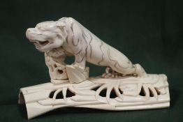 A MEIJI PERIOD CARVED IVORY JAPANESE TIGER ON A PIERCED BRANCH BASE, the tiger with incised stripe