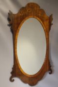 A 19TH CENTURY MAHOGANY SHAPED WALL MIRROR, the oval glass within a cross banded border, with furthe