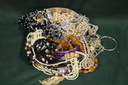 A TIN OF MOSTLY NECKLACES TO INCLUDE AN AMBER STYLE EXAMPLE, BANGLE ETC.