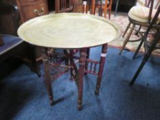 AN EASTERN BRASS TOPPED FOLDING TABLE