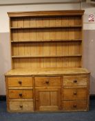 A LARGE ANTIQUE PINE KITCHEN DRESSER, having enclosed plate rack, the base with an arrangements of