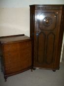 AN OAK LOCKING HALL CUPBOARD AND A BOW FRONTED CHEST OF FIVE DRAWERS